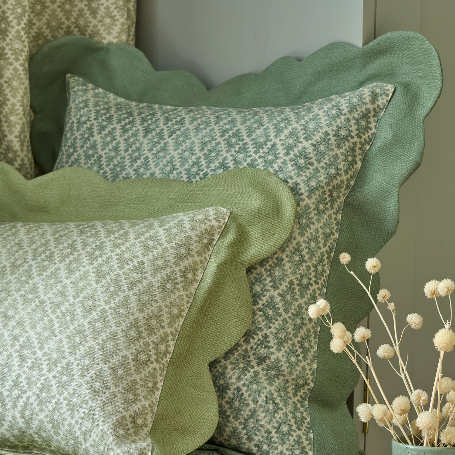 Cushions in a green and neutral printed linen fabric with a geometric pattern
