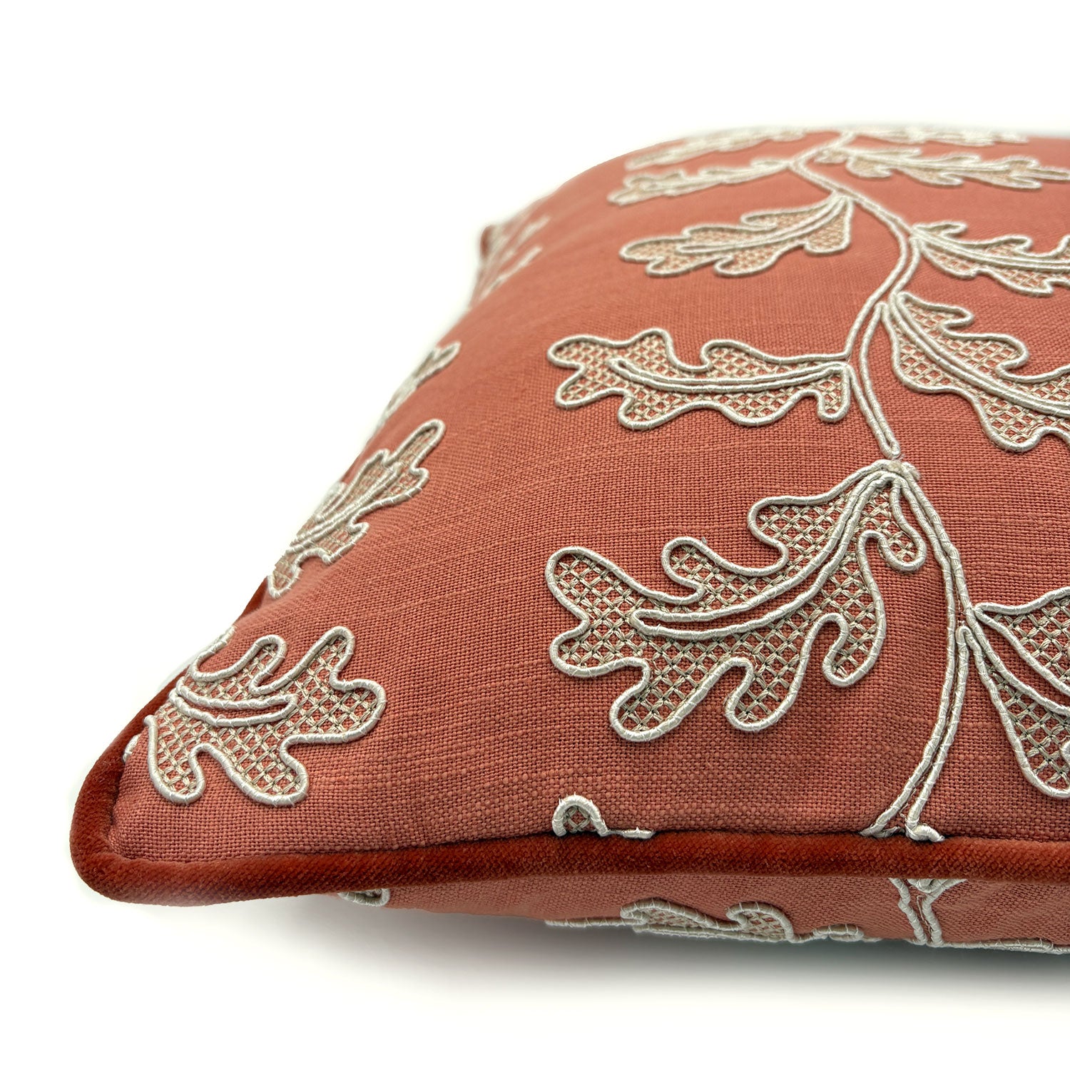 Decorative coral cushion with a off-white leaf pattern.
