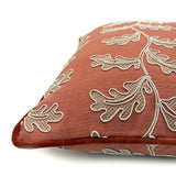 Decorative coral cushion with a off-white leaf pattern.
