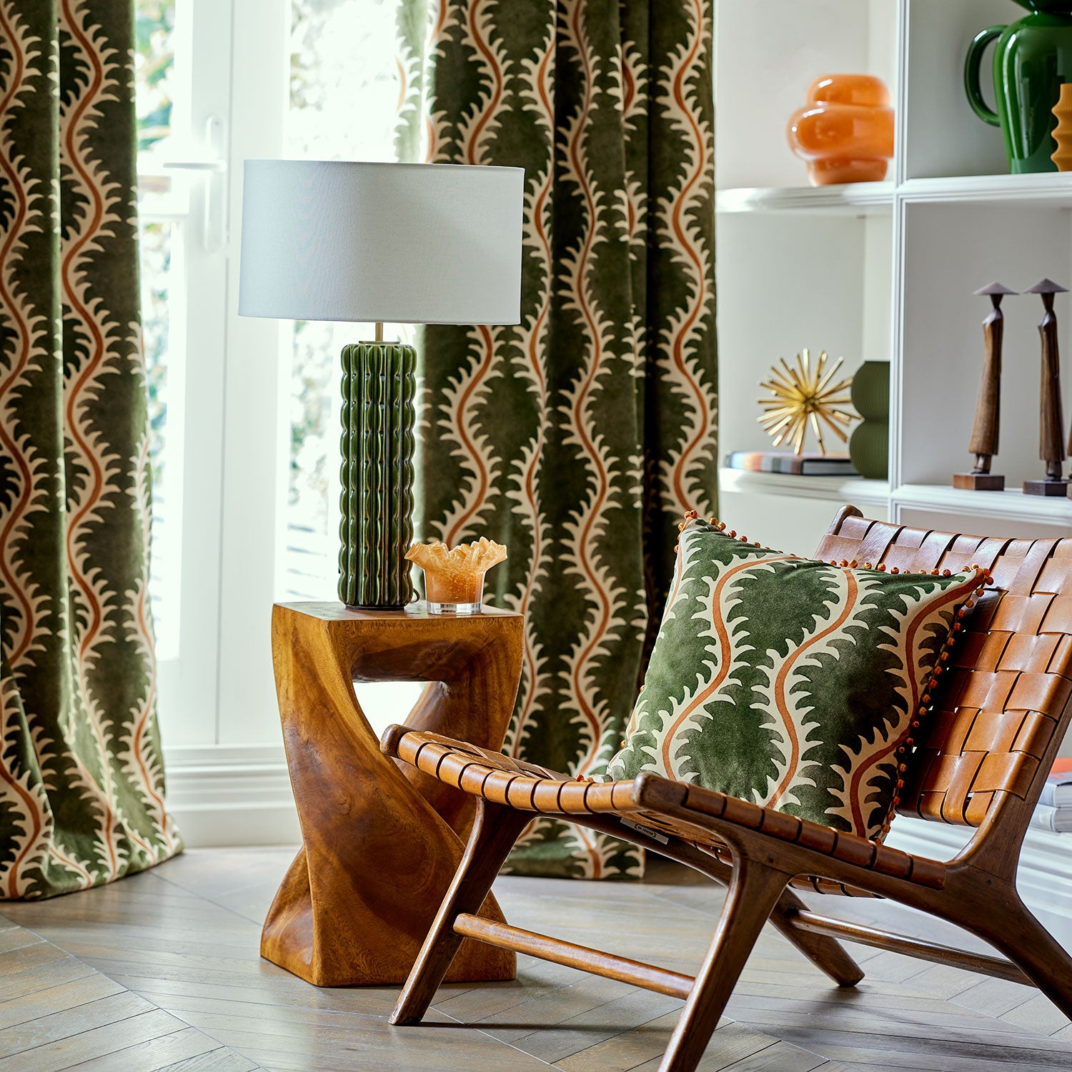 Curtains and cushion in a printed velvet fabric in green and orange featuring a stylized fern pattern.