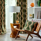 Curtains and cushion in a printed velvet fabric in green and orange featuring a stylized fern pattern.