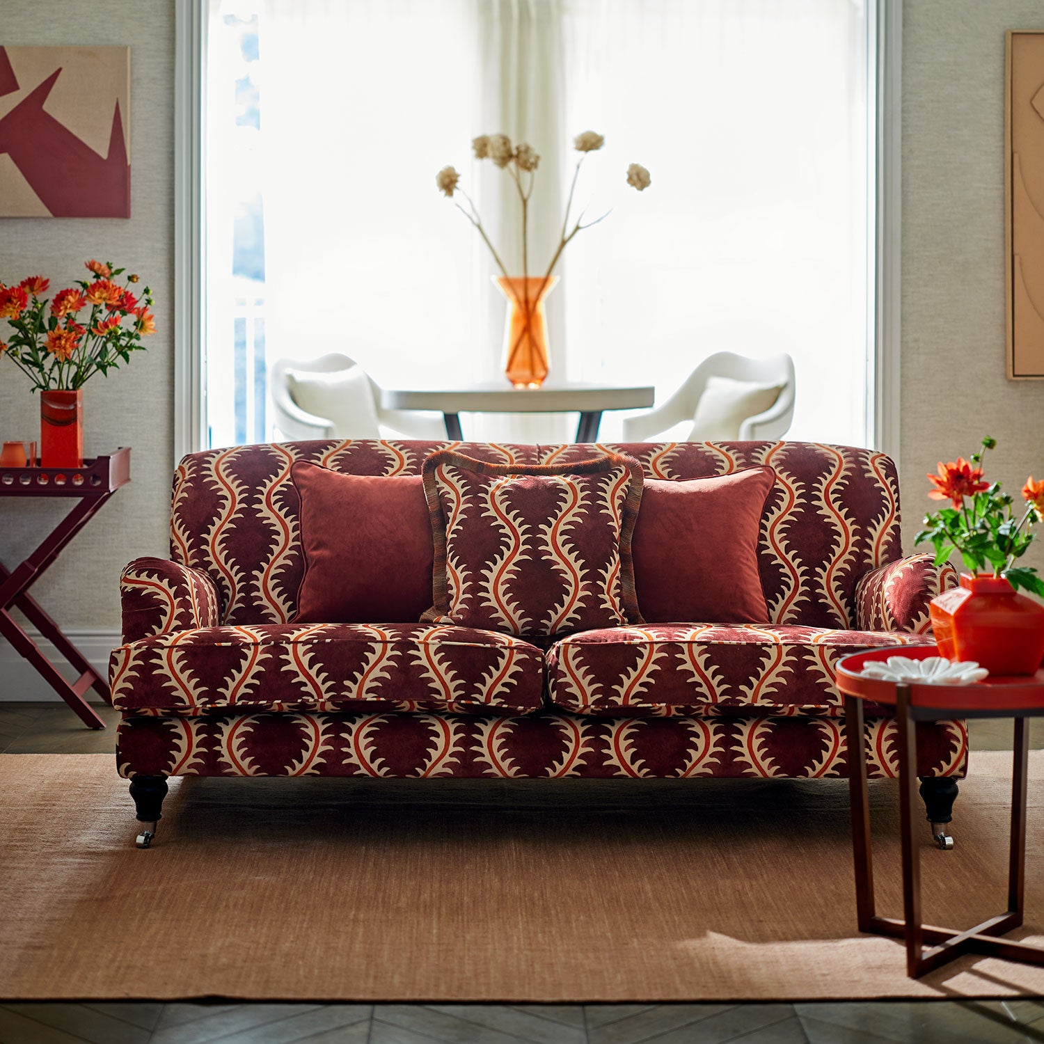 Sofa upholstered in a printed velvet fabric in purple and orange featuring a stylized fern pattern.