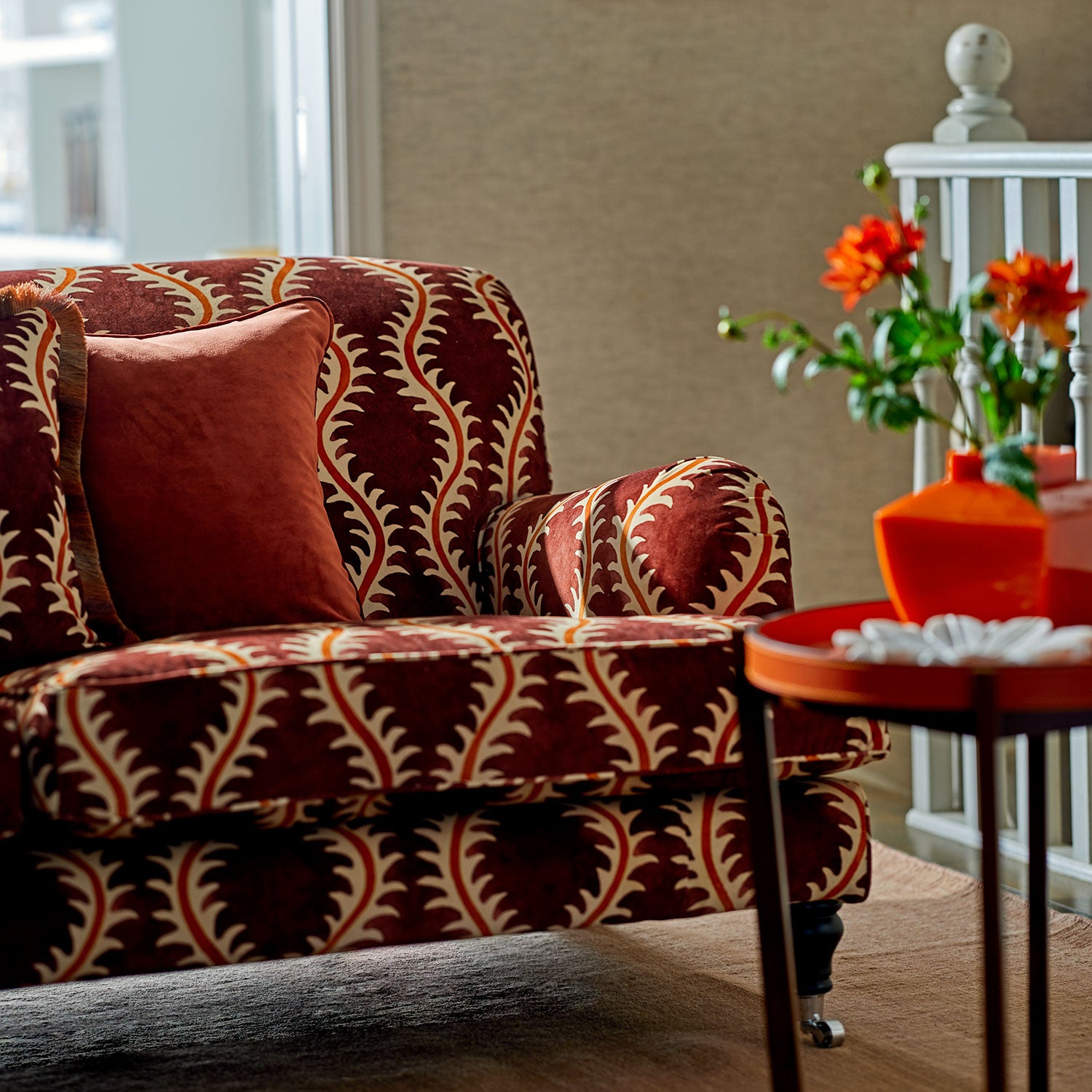 Sofa upholstered in a printed velvet fabric in purple and orange featuring a stylized fern pattern.