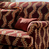 Sofa upholstered in a printed velvet fabric in purple and orange featuring a stylized fern pattern.