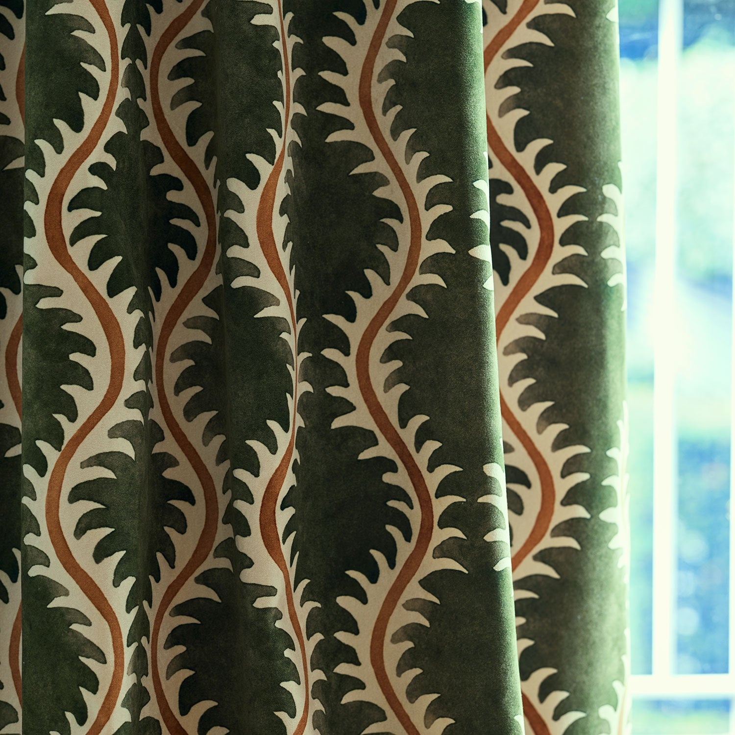 Curtain in a printed velvet fabric in green and orange featuring a stylized fern pattern.