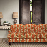 Sofa upholstered in a printed velvet fabric in brown and orange featuring a stylized fern pattern.