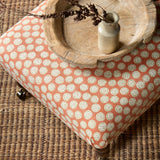 Footstool covered in a linen printed with a subtle all-over repeat in orange, cream and black