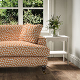 Sofa covered in a linen printed with a subtle all-over repeat in orange, cream and black