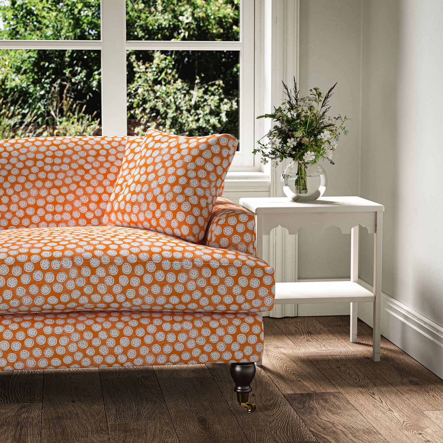 Sofa covered in a linen printed with a subtle all-over repeat in orange, cream and black