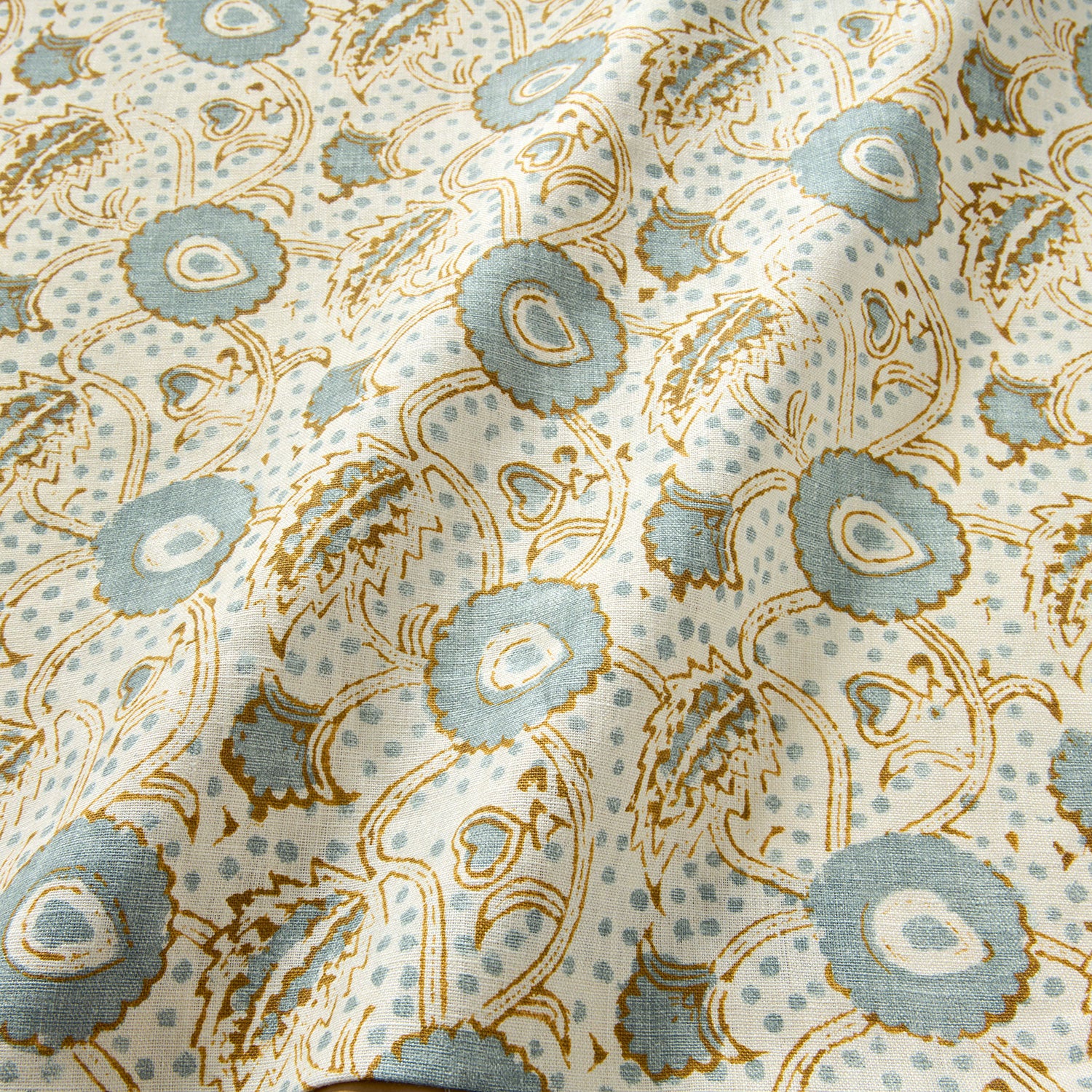 A stylised floral printed on linen fabric in green, orange and cream
