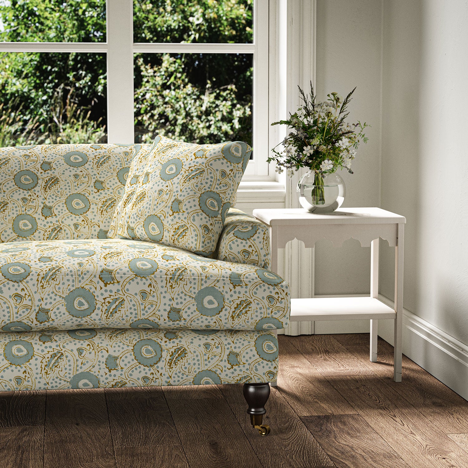 Sofa covered with a stylised floral printed on linen fabric in green, orange and cream