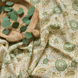 A stylised floral printed on linen fabric in green, orange and cream