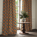 Curtains made from a printed linen fabric in blue, orange, black and off white featuring a mirrored ribbon pattern.