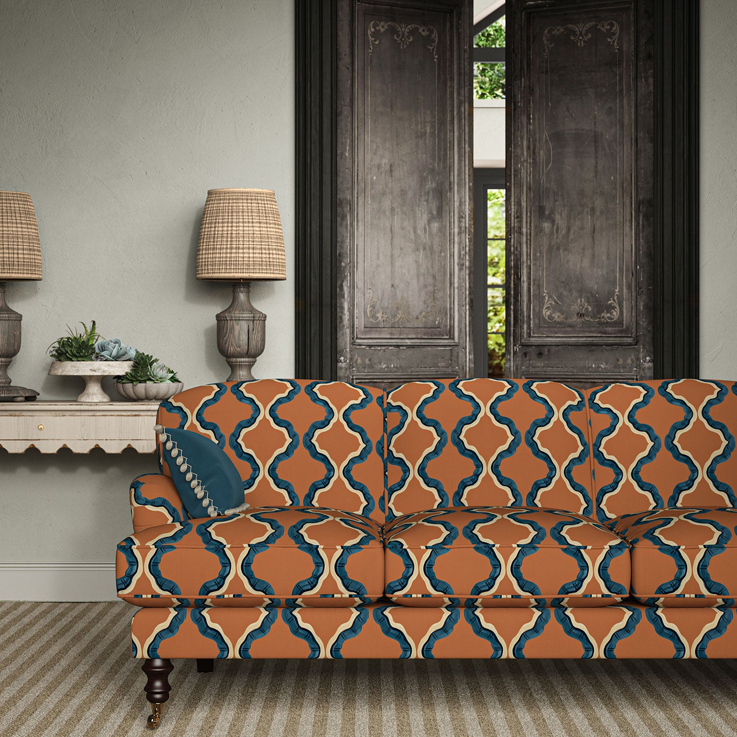 Sofa upholstered in a printed linen fabric in blue, orange, black and off white featuring a mirrored ribbon pattern.