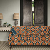 Sofa upholstered in a printed linen fabric in blue, orange, black and off white featuring a mirrored ribbon pattern.