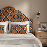 Headboard upholstered in a printed linen fabric in blue, orange, black and off white featuring a mirrored ribbon pattern.