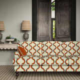 Sofa upholstered in a printed linen fabric in blue, orange, brown and off white featuring a mirrored ribbon pattern.
