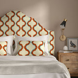 Headboard upholstered in a printed linen fabric in blue, orange, brown and off white featuring a mirrored ribbon pattern.