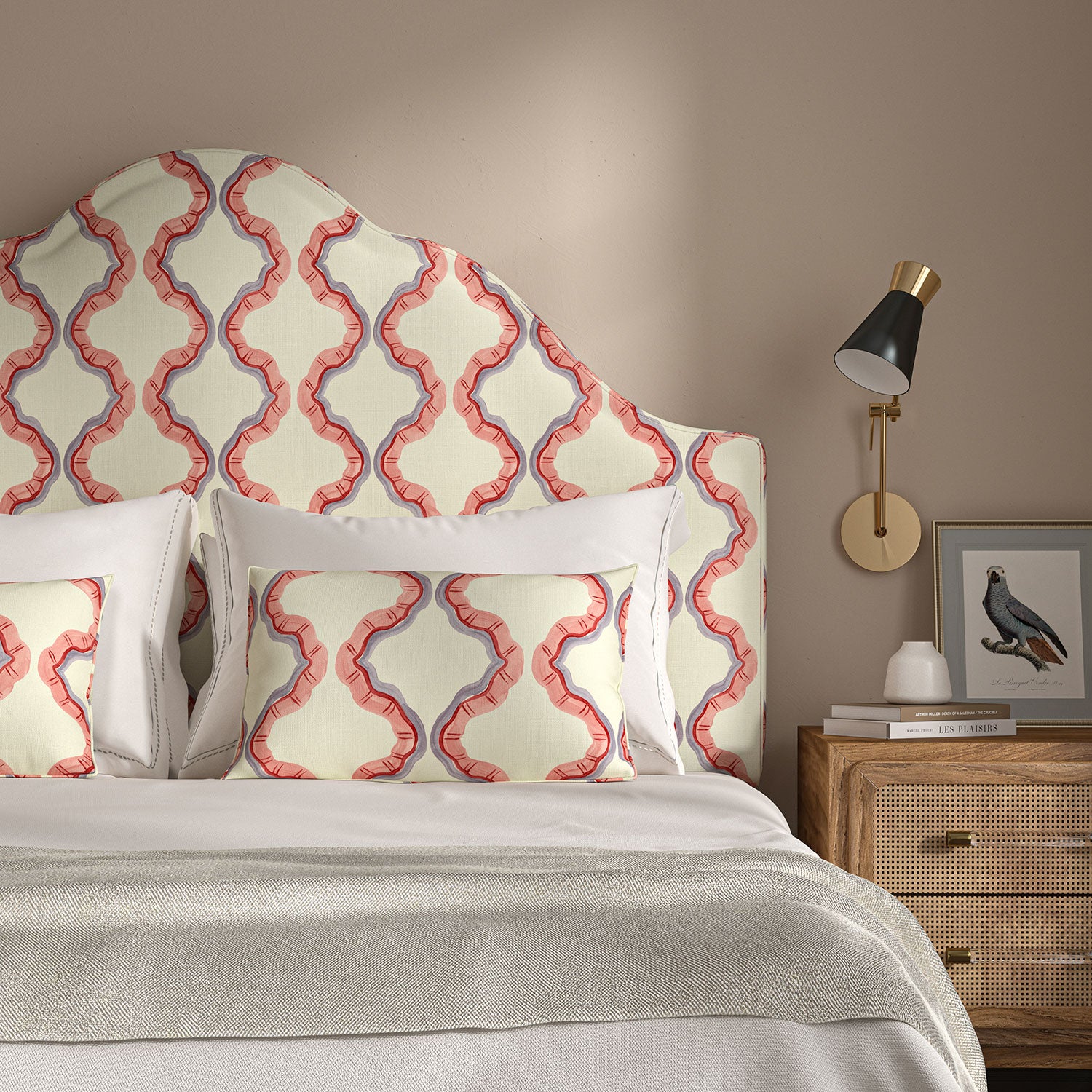 Headboard upholstered in a printed linen fabric in pink, purple, red, and off white featuring a mirrored ribbon pattern.