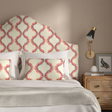 Headboard upholstered in a printed linen fabric in pink, purple, red, and off white featuring a mirrored ribbon pattern.