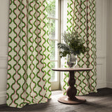 Curtains made from a printed linen fabric in pink, green, and off white featuring a mirrored ribbon pattern.