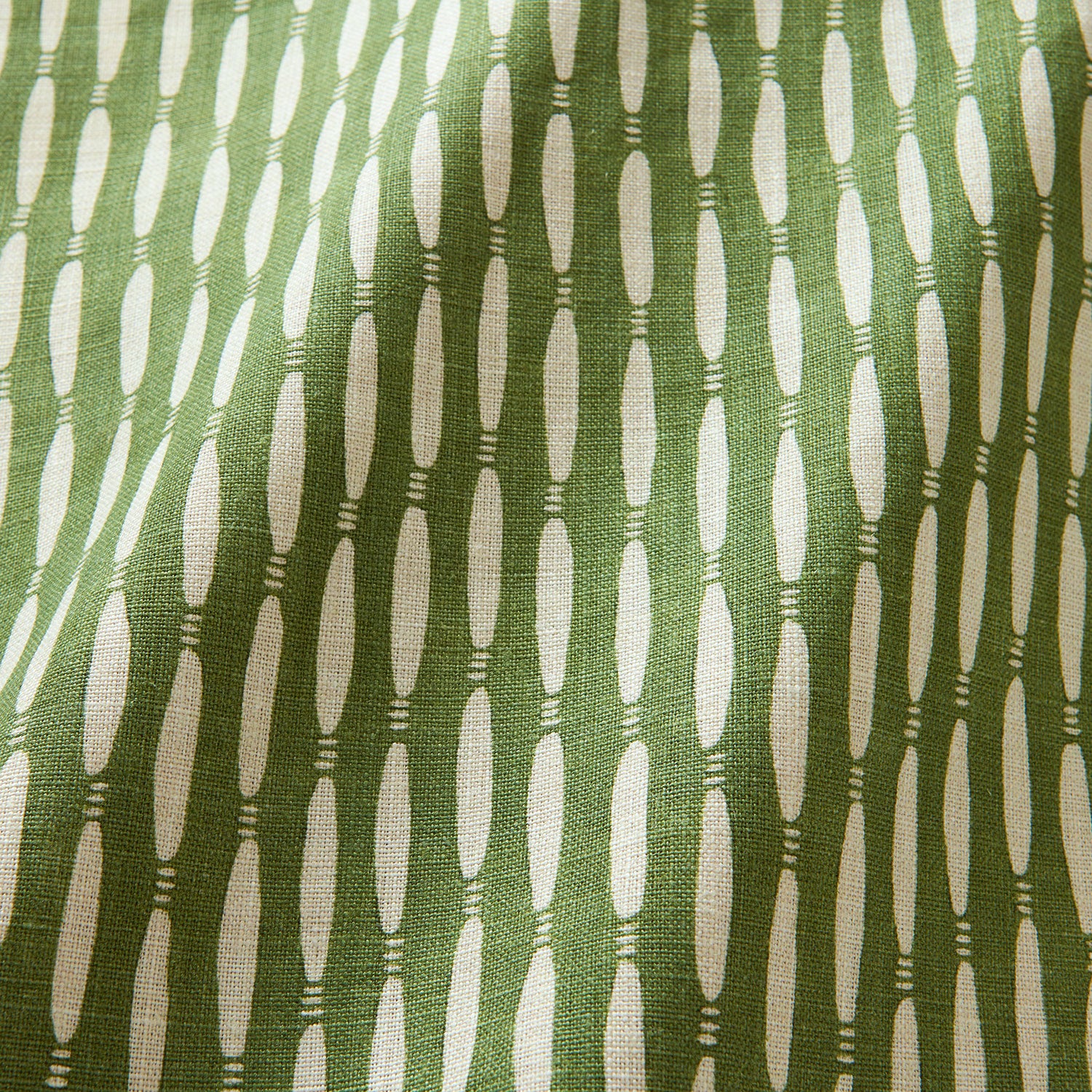 A printed linen fabric sample in green and off white featuring a Japanese print.