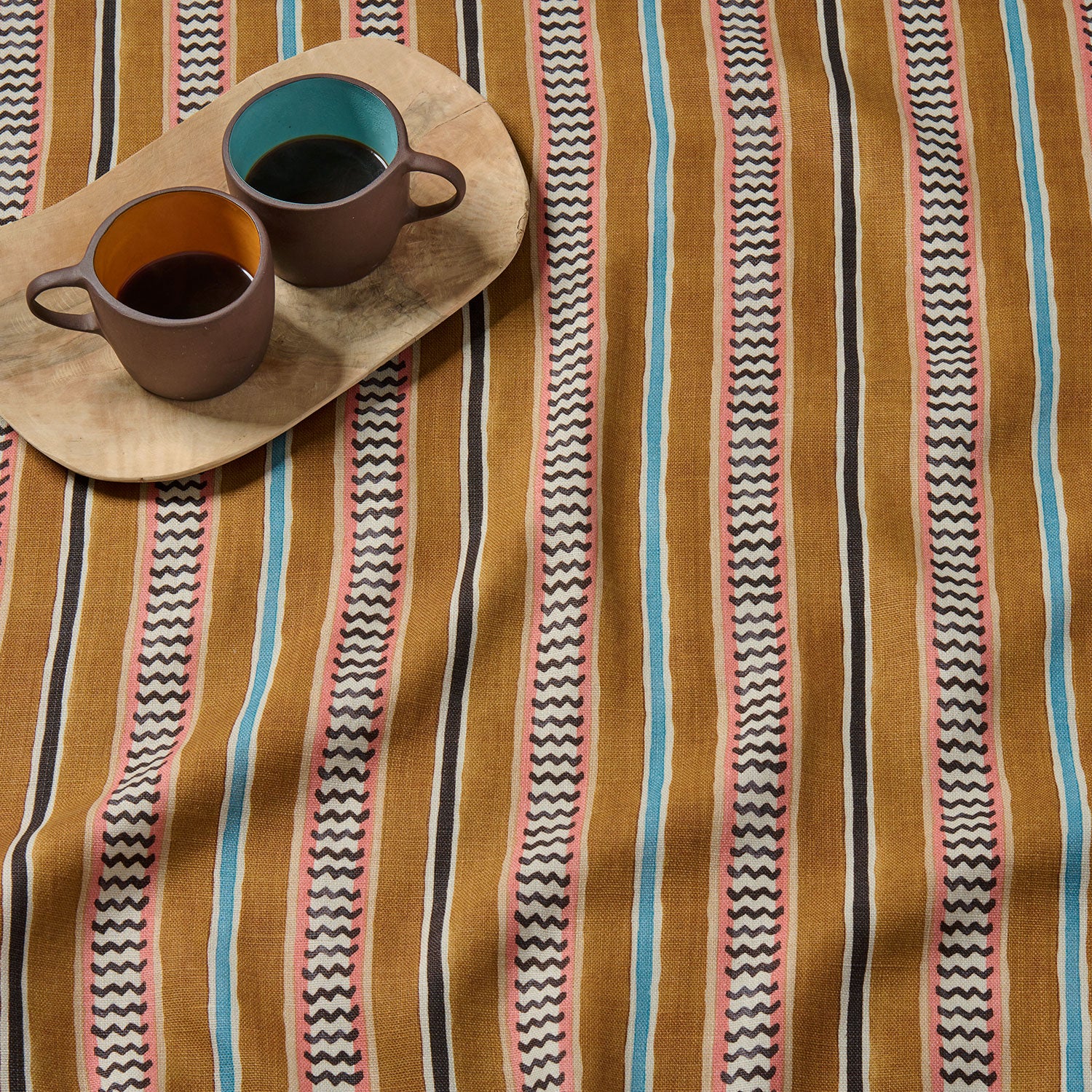 A multicoloured printed linen fabric sample featuring stripes, wavy edges and zigzags.