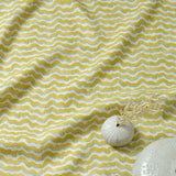 A printed linen fabric sample in yellow, blue and off white featuring a sound wave pattern