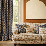 Sofa upholstered in a printed linen fabric sample in orange, blue and off white featuring a stylized coral pattern.