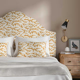 Headboard upholstered in a printed linen fabric sample in orange, blue and off white featuring a stylized coral pattern.