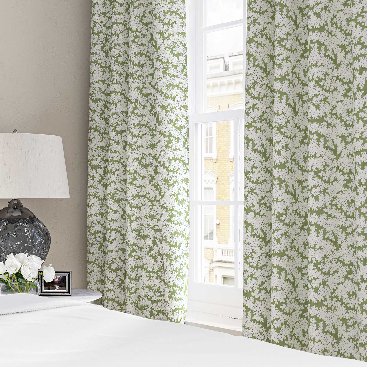 Curtains made from a printed linen fabric sample in green, blue and off white featuring a stylized coral pattern.