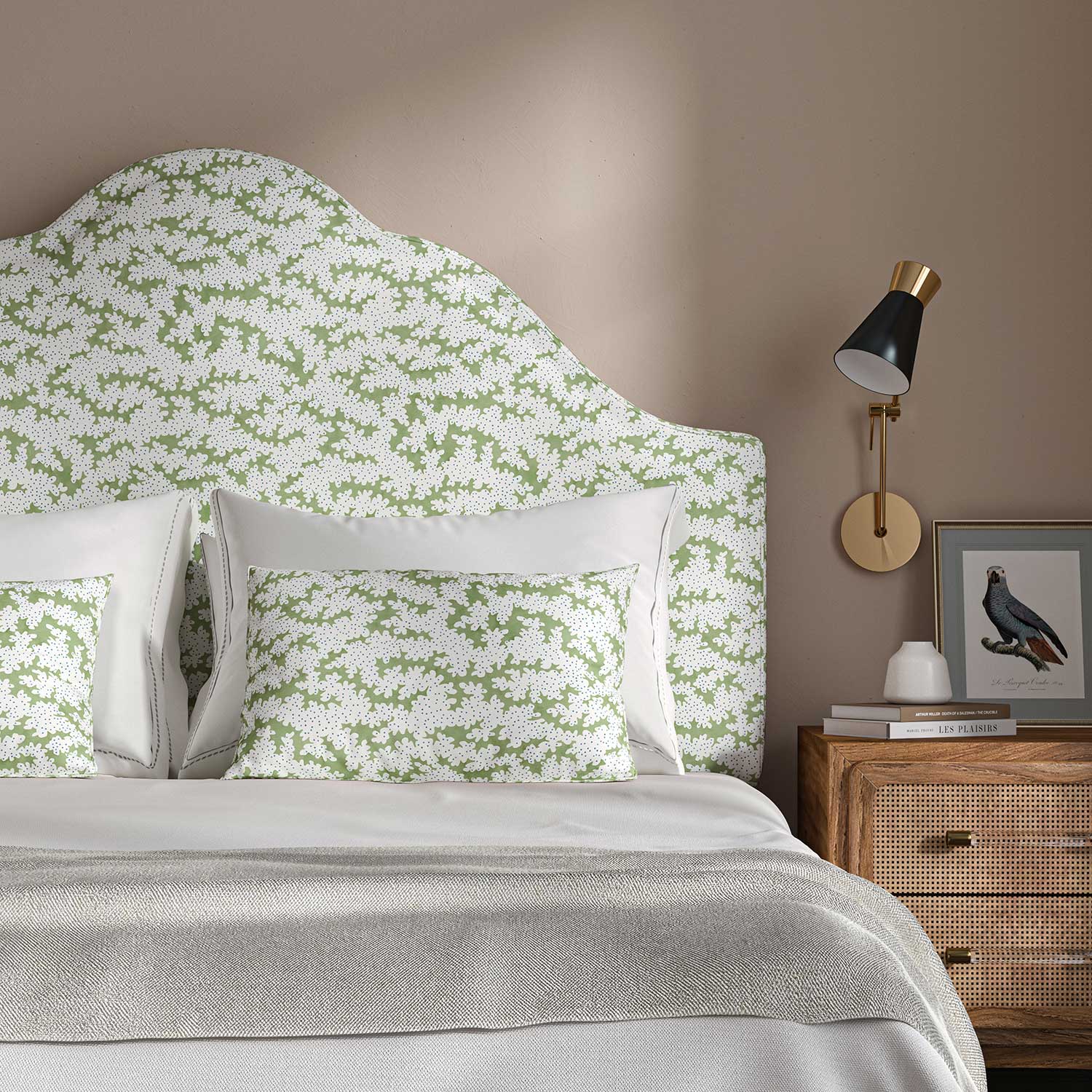 Headboard upholstered in a printed linen fabric sample in green, blue and off white featuring a stylized coral pattern.