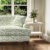Sofa upholstered in a printed linen fabric sample in green, blue and off white featuring a stylized coral pattern.
