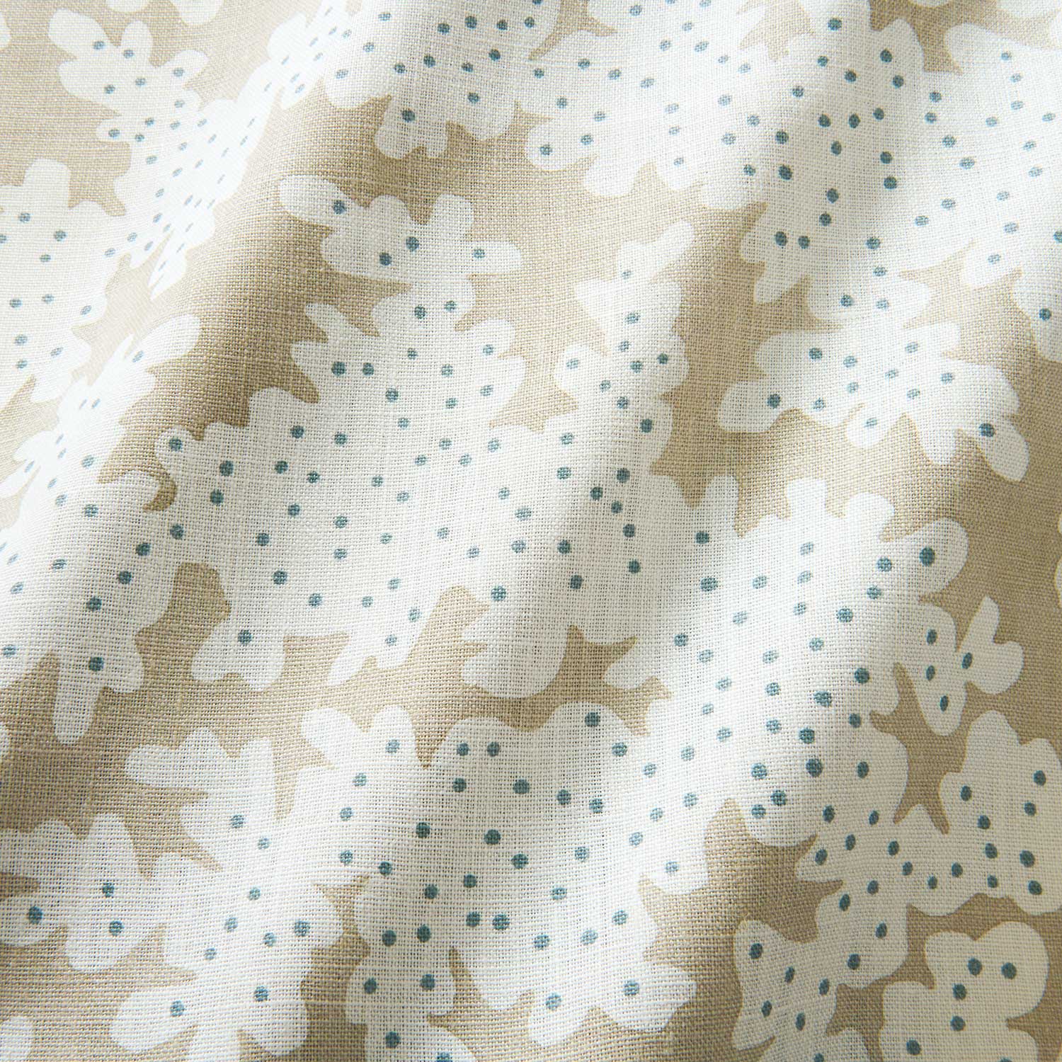 A printed linen fabric sample in brown, blue and off white featuring a stylized coral pattern.