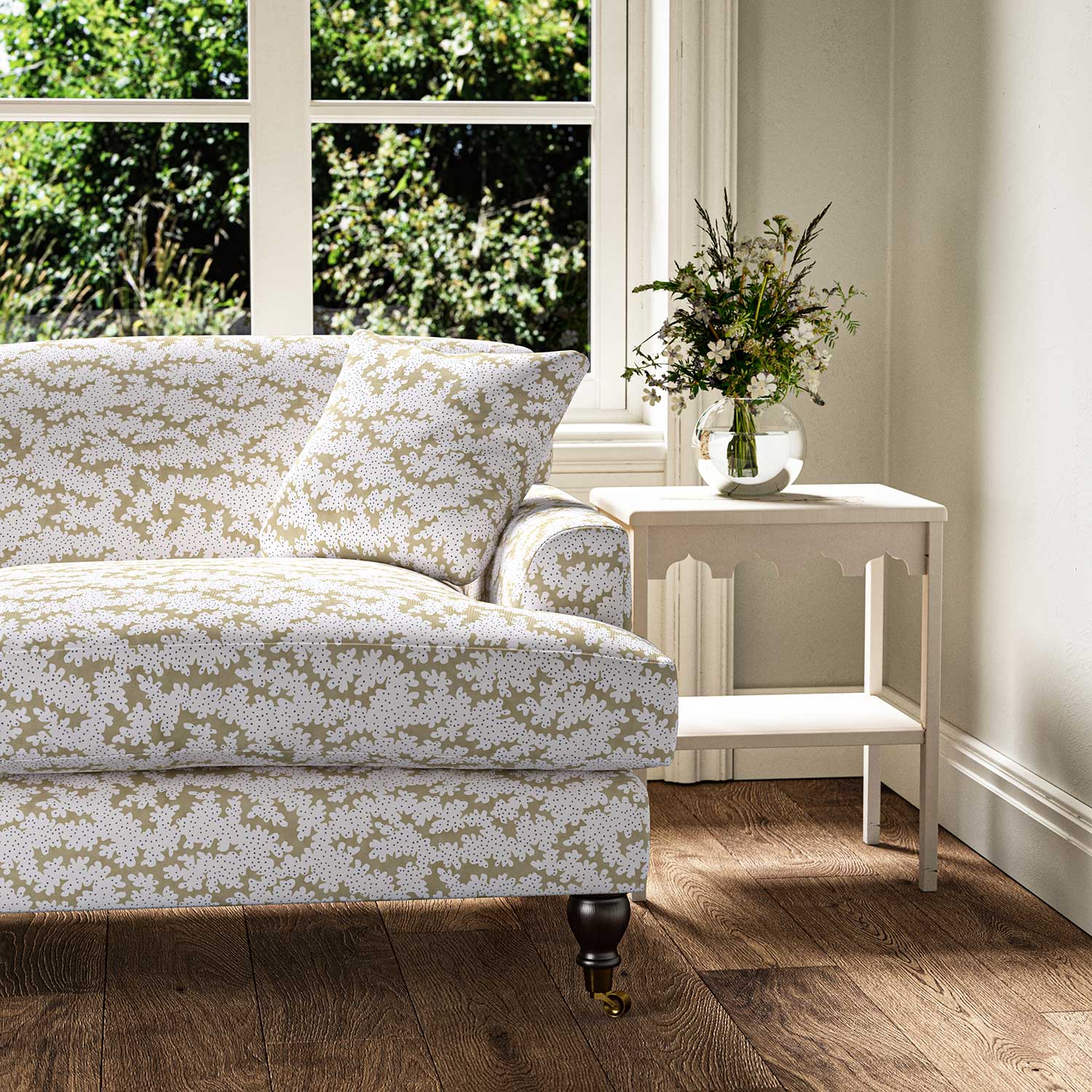 Sofa upholstered in a printed linen fabric sample in brown, blue and off white featuring a stylized coral pattern.