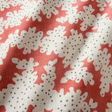 A printed linen fabric sample in red, brown and off white featuring a stylized coral pattern.