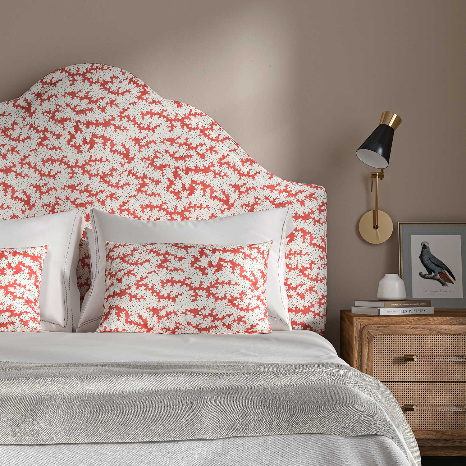 Headboard upholstered in a printed linen fabric sample in red, brown and off white featuring a stylized coral pattern.