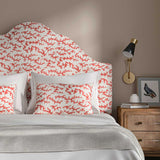 Headboard upholstered in a printed linen fabric sample in red, brown and off white featuring a stylized coral pattern.