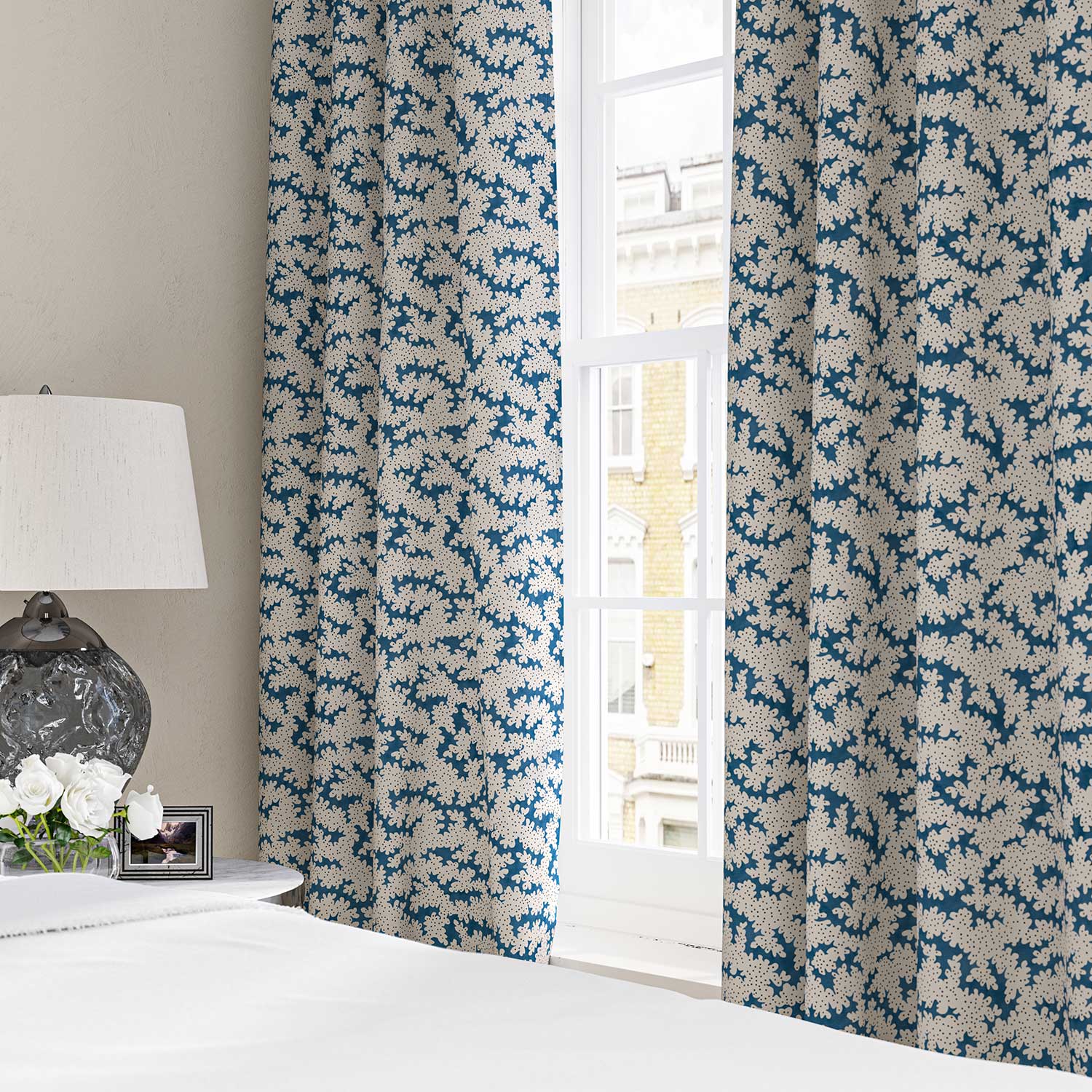 Curtains made in a printed linen fabric sample in blue, black and off white featuring a stylized coral pattern.