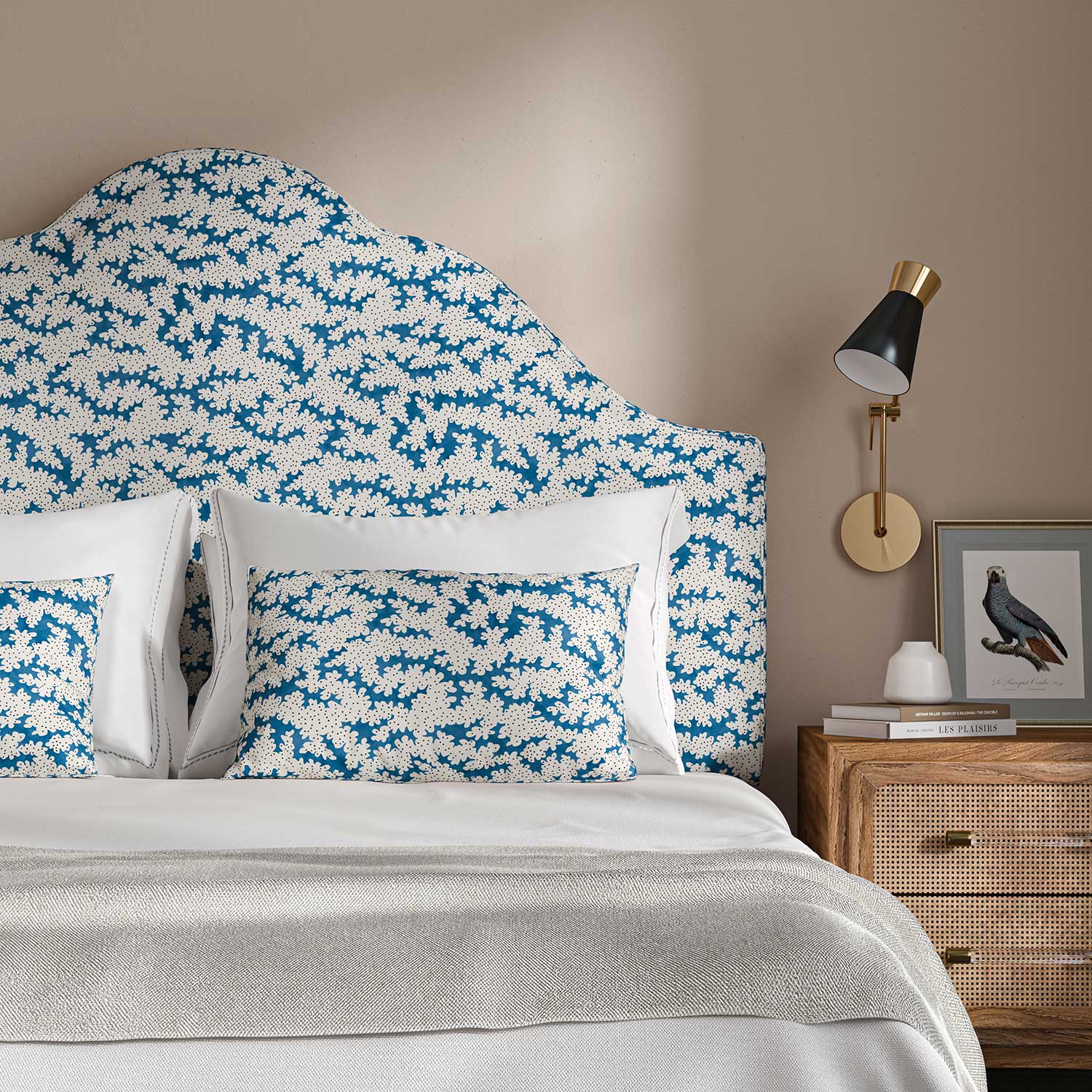Headboard upholstered in a printed linen fabric sample in blue, black and off white featuring a stylized coral pattern.