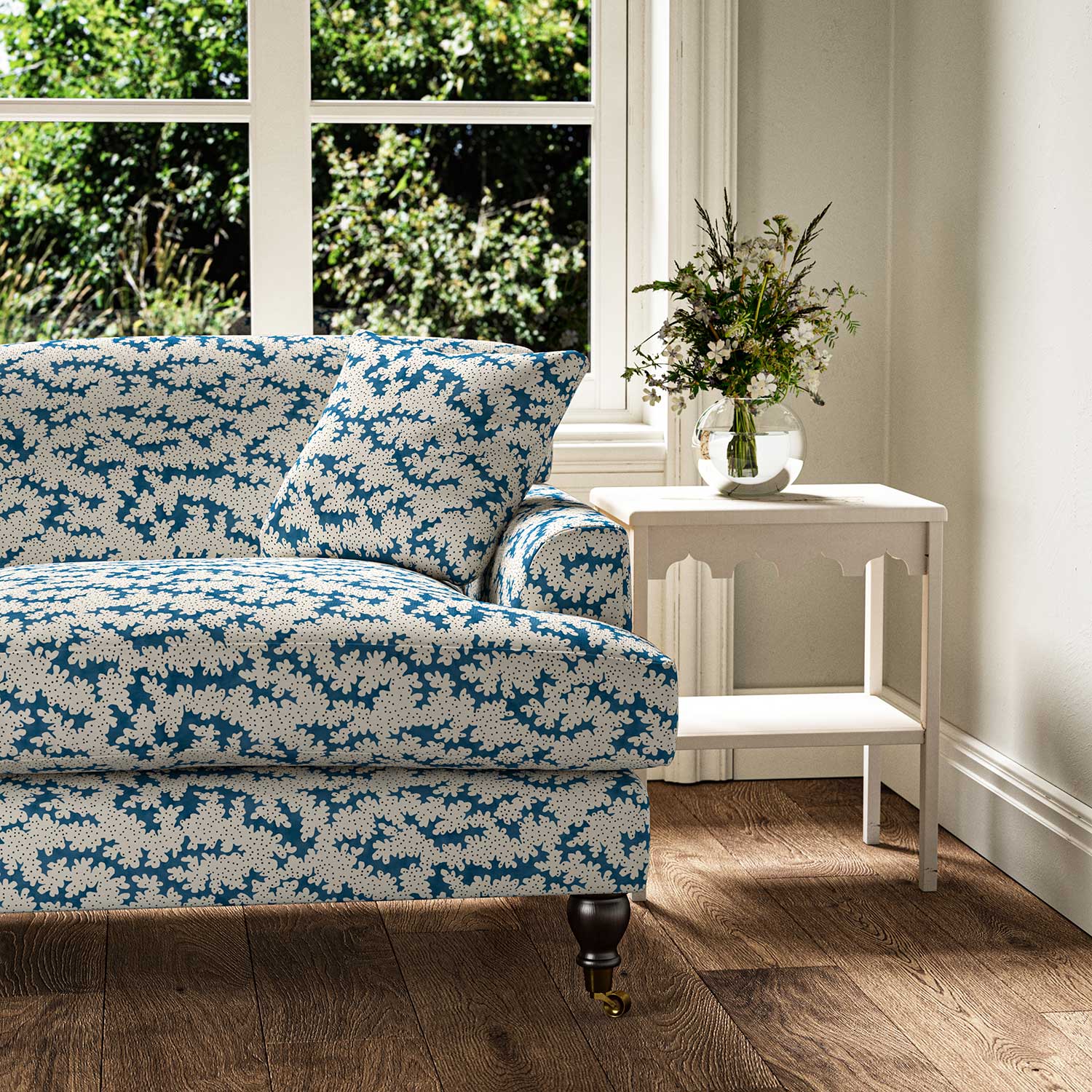 Sofa upholstered in a printed linen fabric sample in blue, black and off white featuring a stylized coral pattern.