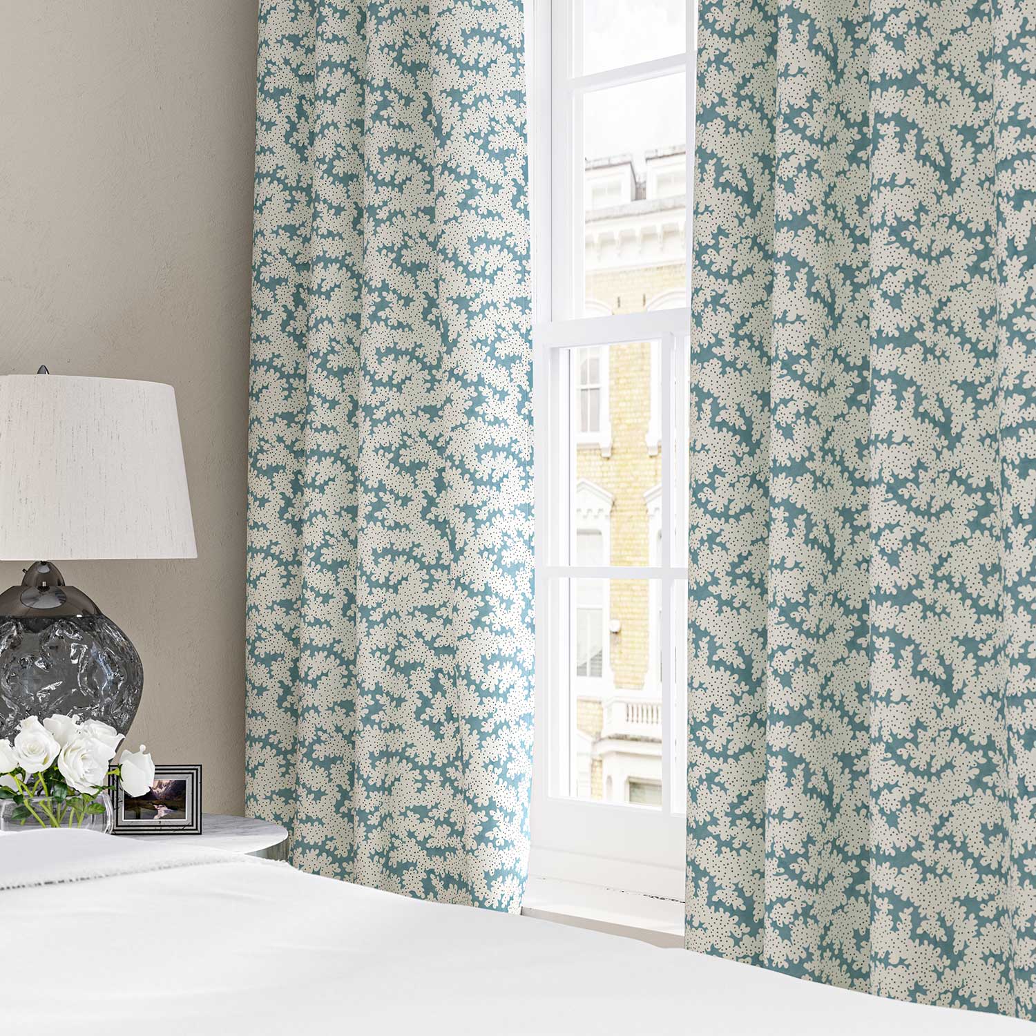 Curtains made from a printed linen fabric sample in blue, black and off white featuring a stylized coral pattern.