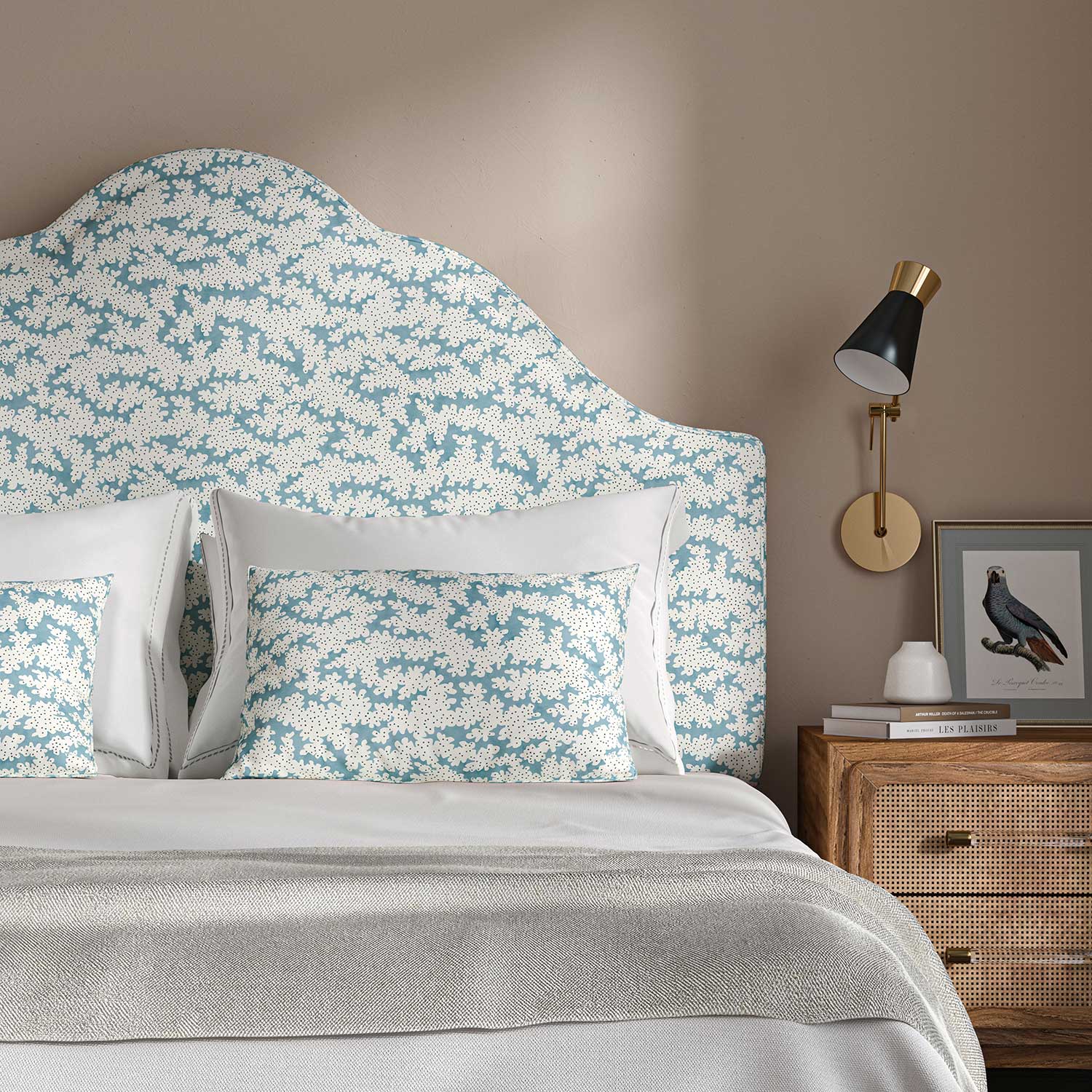 Headboard upholstered in a printed linen fabric sample in blue, black and off white featuring a stylized coral pattern.