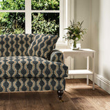 Sofa upholstered in a printed linen fabric sample in blue, orange and off white featuring a stylized fern pattern.