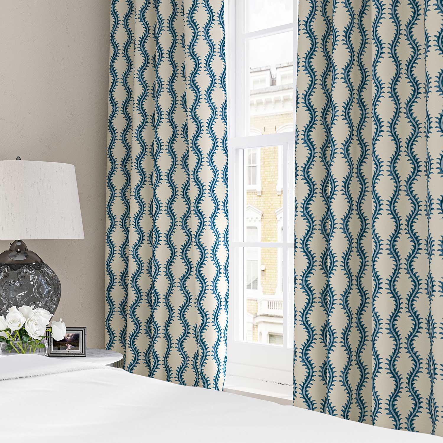 Curtains made from a printed linen fabric sample in blue and off white featuring a stylized fern pattern.