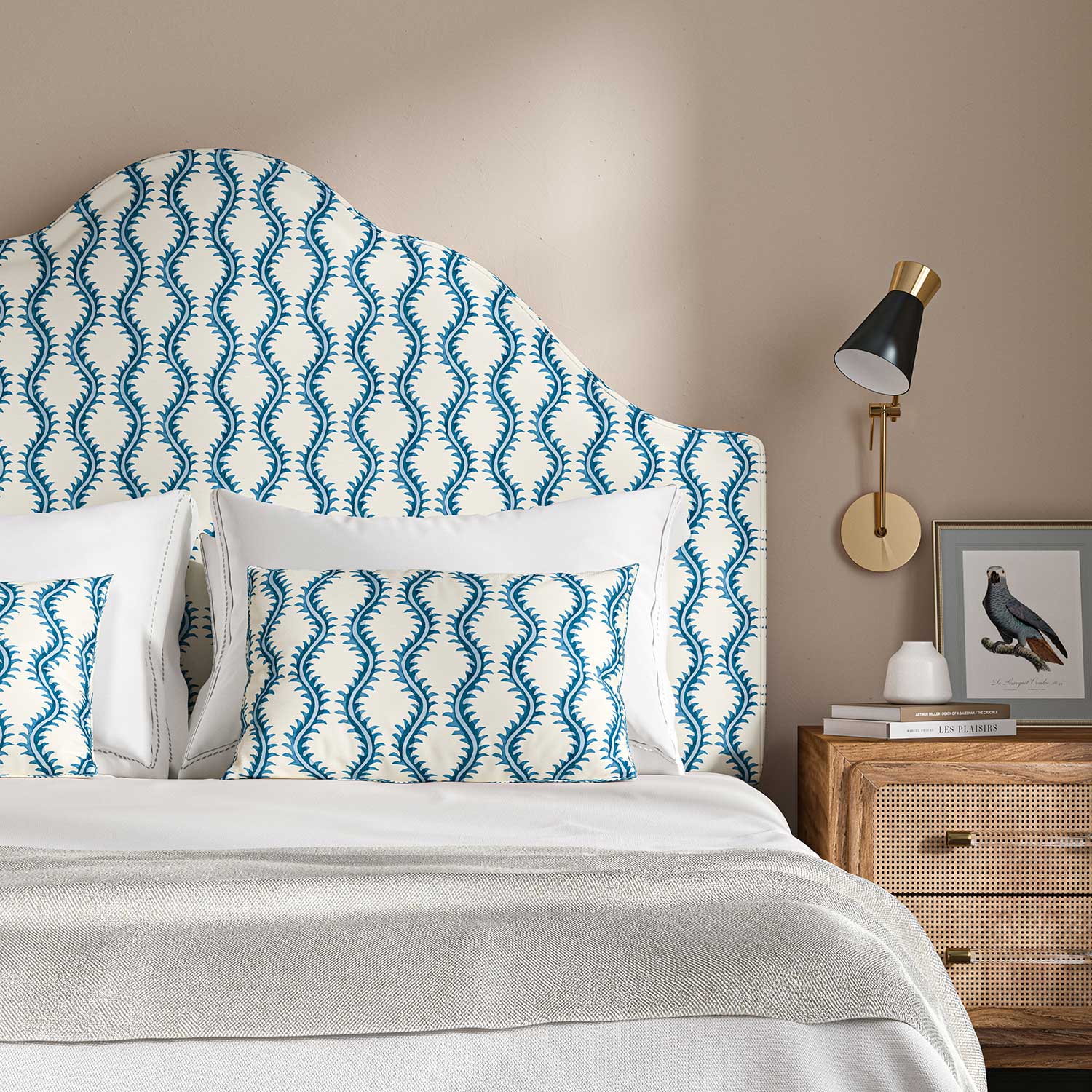 Headboard upholstered in a printed linen fabric sample in blue and off white featuring a stylized fern pattern.