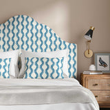 Headboard upholstered in a printed linen fabric sample in blue and off white featuring a stylized fern pattern.