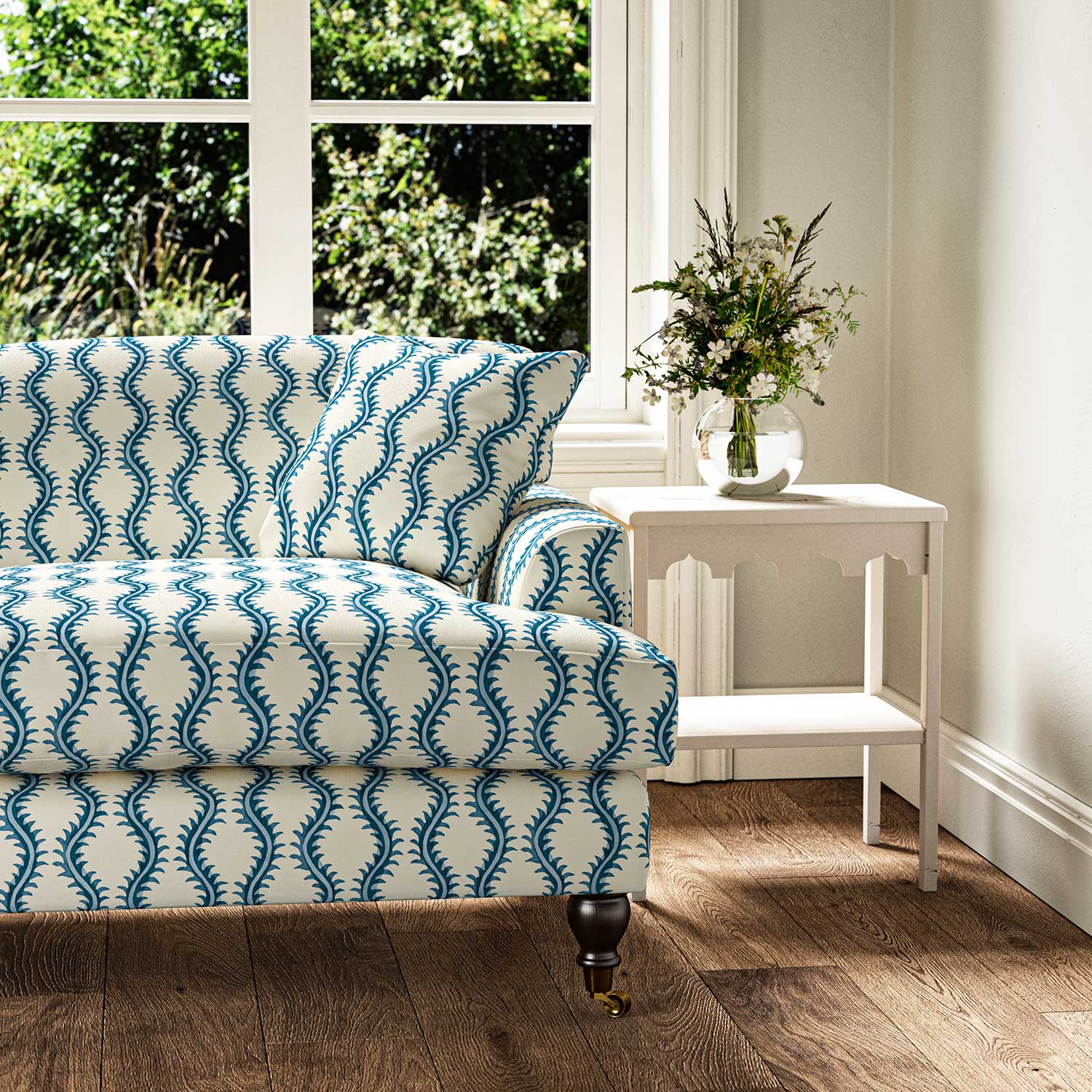 Sofa upholstered in a printed linen fabric sample in blue and off white featuring a stylized fern pattern.