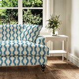 Sofa upholstered in a printed linen fabric sample in blue and off white featuring a stylized fern pattern.