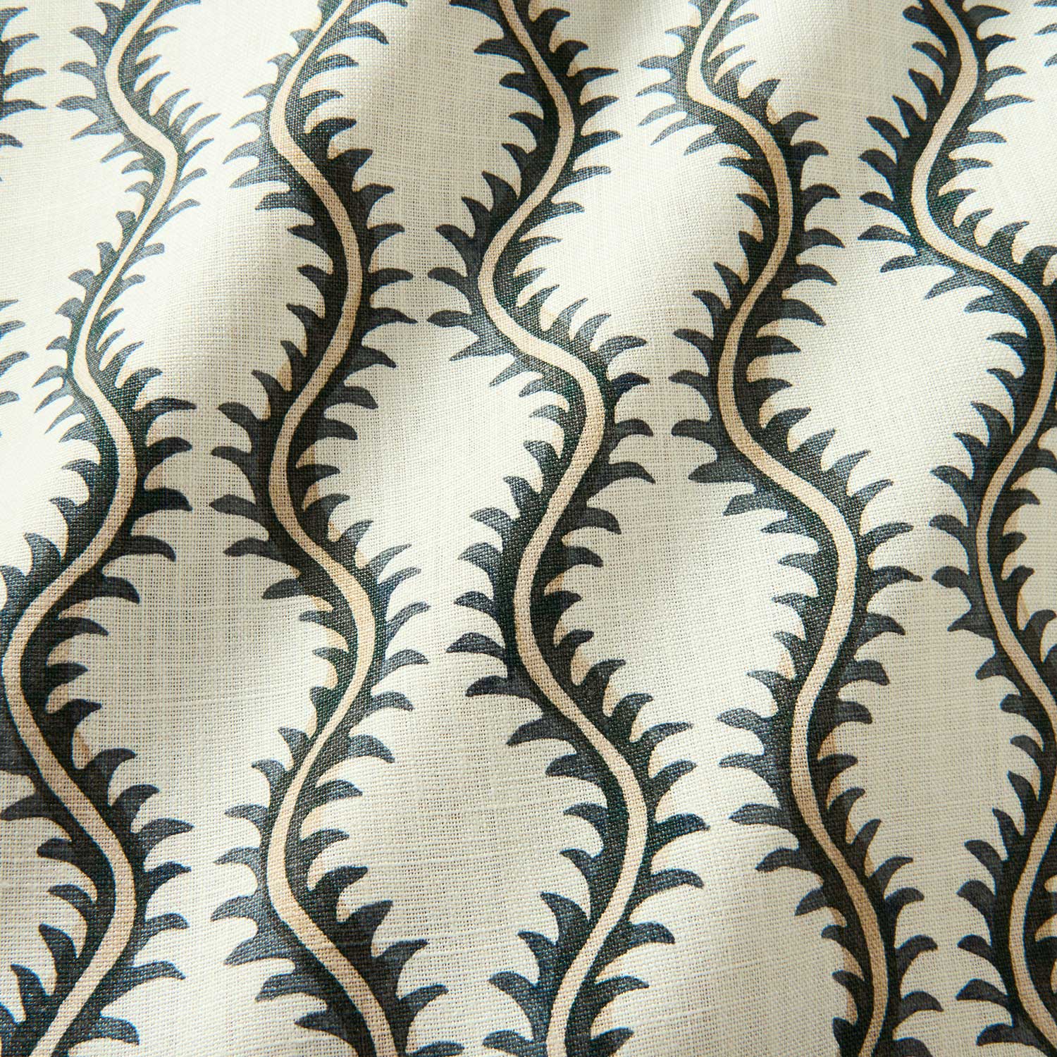 A printed linen fabric sample in green and off white featuring a stylized fern pattern.